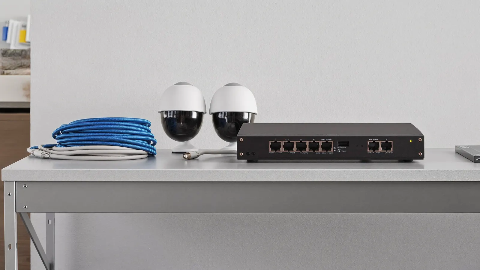 Grabador, switch PoE, cable de red y cable coaxial junto a dos cámaras de seguridad